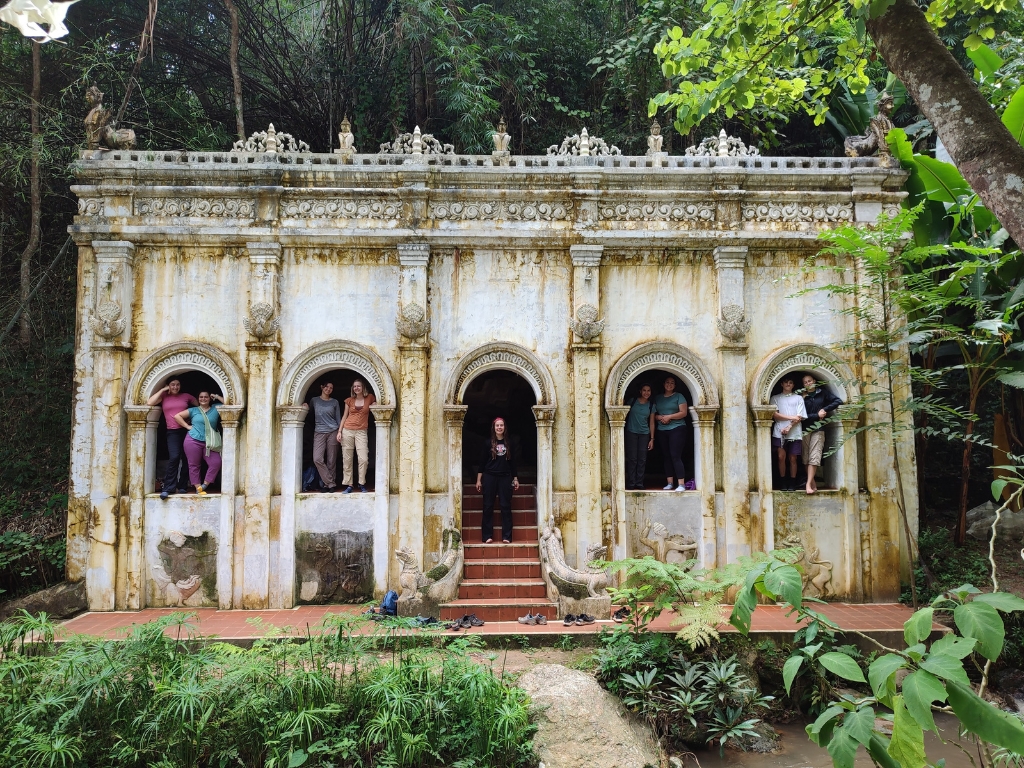 Students peeking out the windows of a temple in Thailand jungle