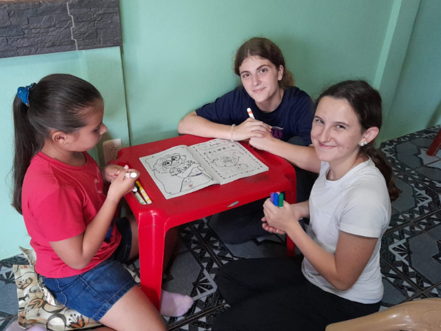 sitting with host sister red table coloring writing