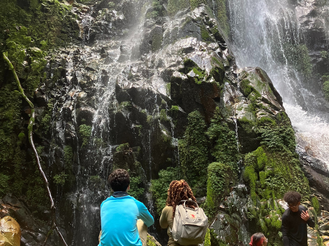 two students sitting looking up at waterfall