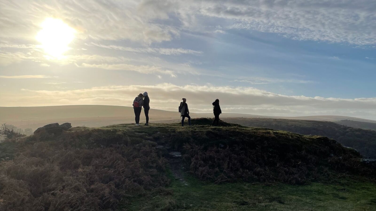 students in countryside viewing sunset from a ridge